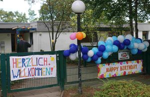 Viele Luftballons und bunt beschriebene Banner an einem Zaun