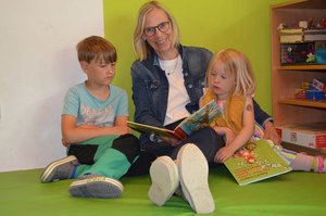 Eine Frau liest zwei Kindern ein Buch vor